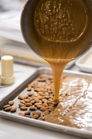 Caramel poured onto whole roasted almonds